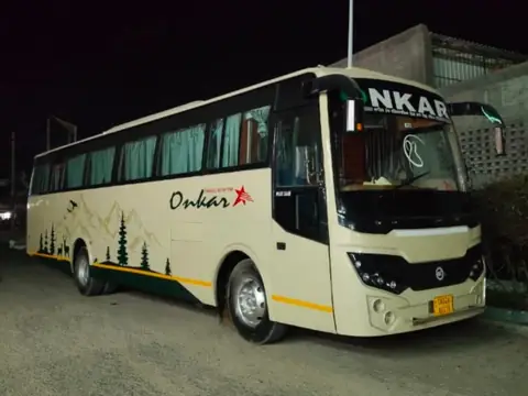 Deluxe coach, cream and forest livery, front three-quarter view at night — built by Guru Kirpa Bus Body Builders, Barnala