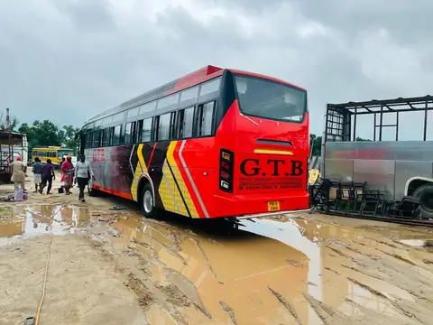 Ordinary bus, red with yellow graphics, side view — built by Guru Kirpa Bus Body Builders, Barnala